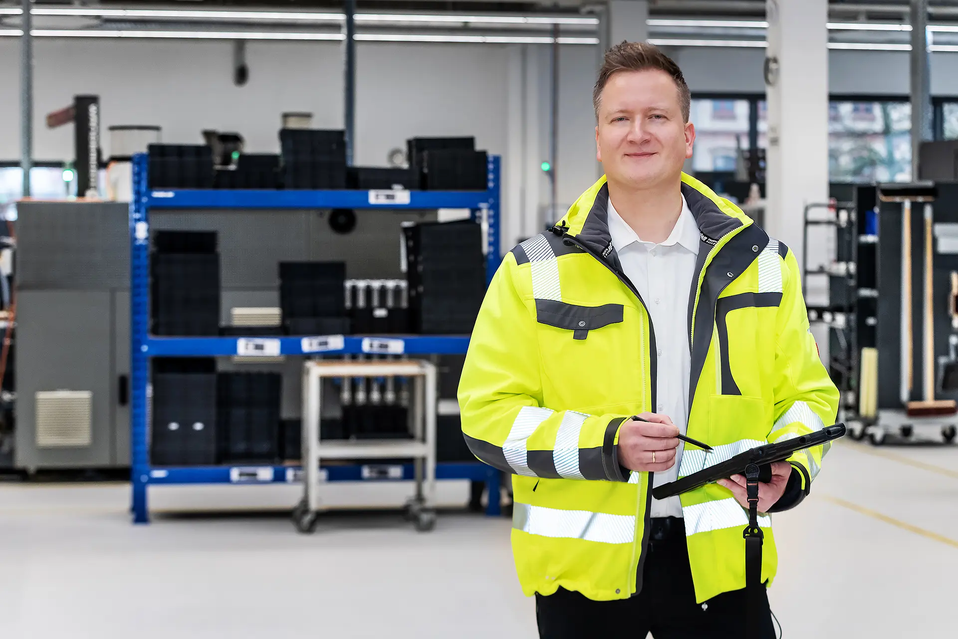 Fachkraft für Arbeitssicherheit der i-Arbeitsschutz Service GmbH mit einem Tablet bei der Betriebsbegehung in einer Industriehalle für maßgeschneiderte Arbeitsschutz-Komplettlösungen.