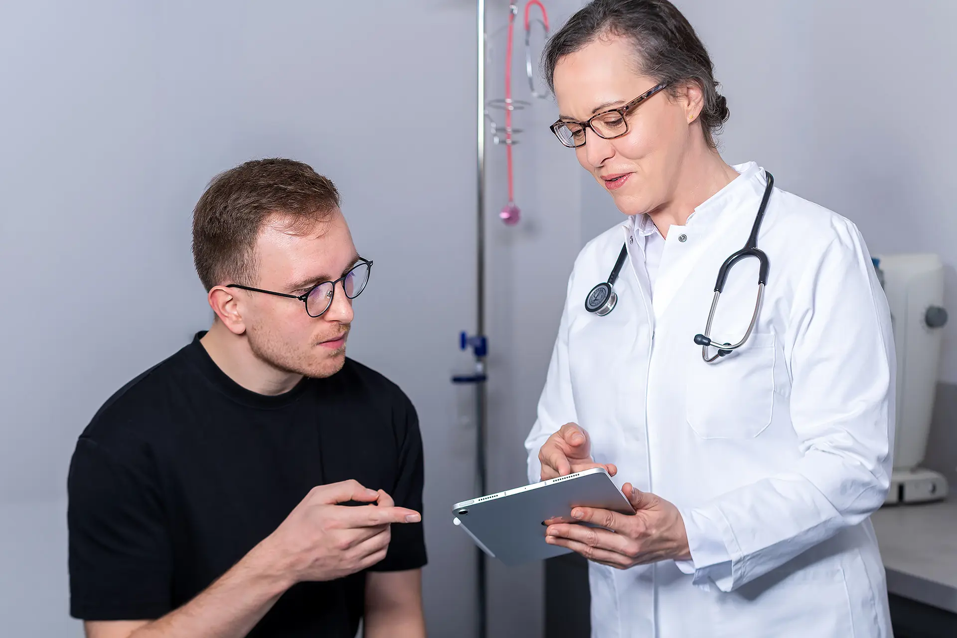 Betriebsärztin der i-Arbeitsschutz Service GmbH berät einen Mitarbeiter mit einem Tablet im Rahmen der integrierten Arbeitsmedizin für Unternehmen.