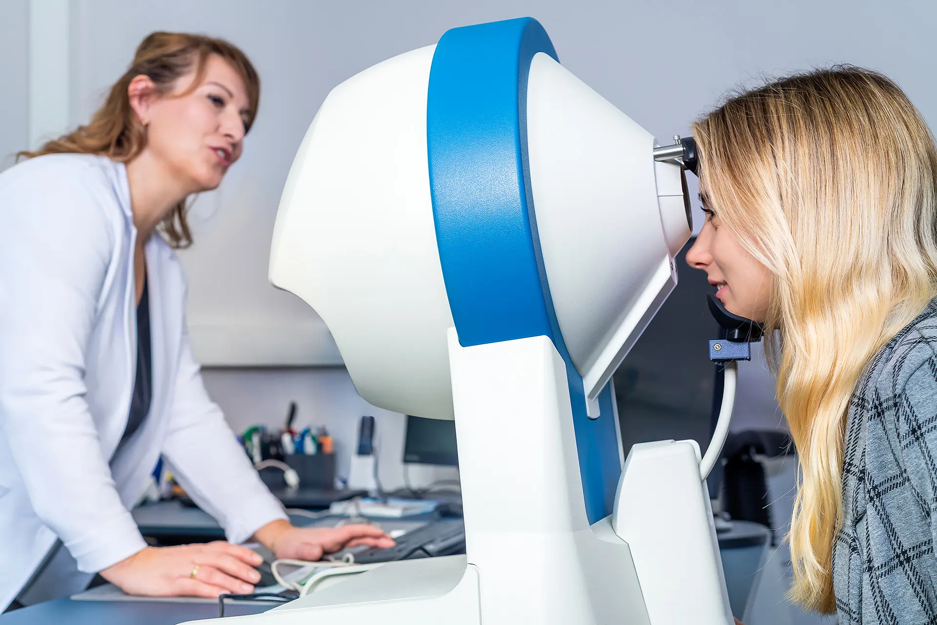 Betriebsärztin der i-Arbeitsschutz Service GmbH führt bei einer Angestellten einen professionellen Sehtest an einem Diagnosegerät für die arbeitsmedizinische Vorsorge durch.